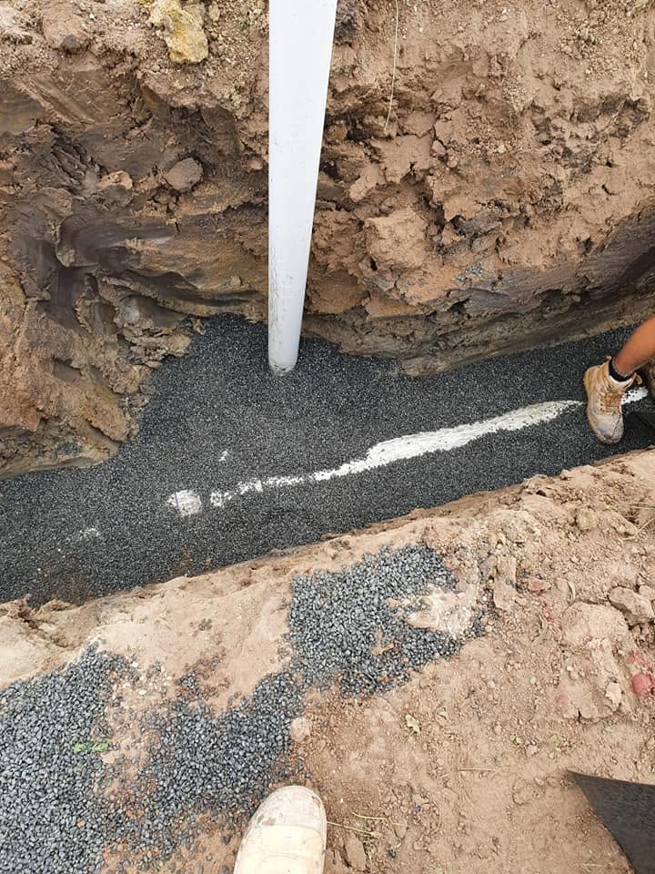 A plumber laying new pipework in a trench